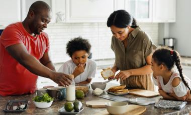 A young African American family is at the dinner table enjoying a meal.